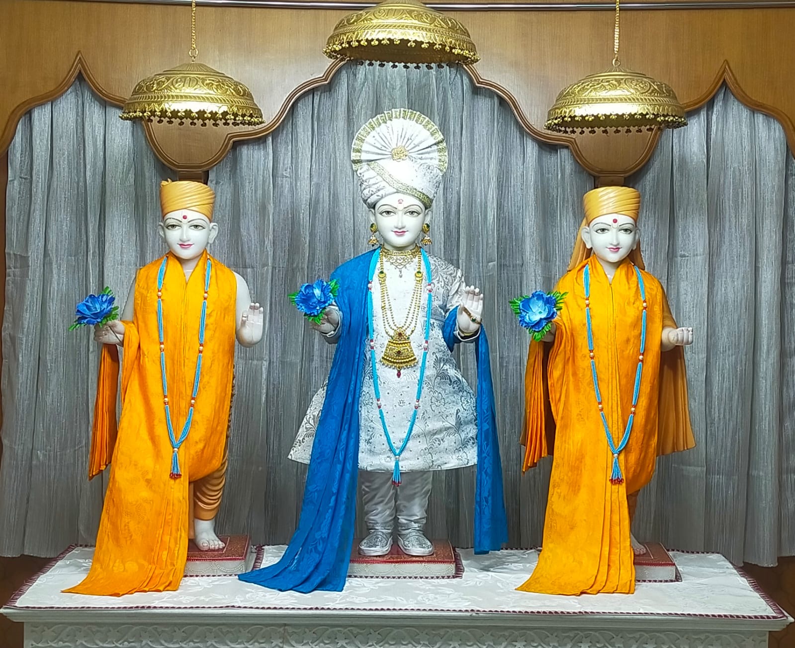 In Centre, Poorna Purushottam Shree Sahajanand Swami Maharaj, On Left Anadi Mul Akshar Murti Shree Gunatitanand Swami and On Right Anadi Mahamukta Shree Gopalanand Swami